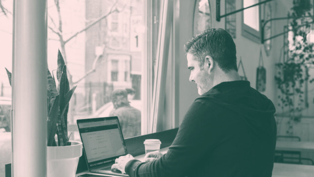 Man Working on Laptop at Cafe Window | Stoke Consulting | Management Consultants